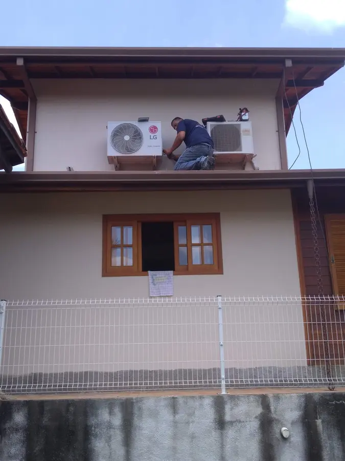 Técnico instalando condensadora na fachada de uma casa